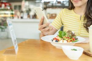 Woman use smartphone to scan QR code to pay in cafe restaurant with a digital payment without cash. Choose menu and order accumulate discount. E wallet, technology, pay online, credit card, bank app. photo