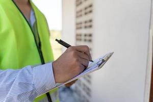 contactor o ingeniero está inspeccionando la construcción y el aseguramiento de la calidad de la nueva casa usando un nivel. ingenieros o arquitectos o contratistas trabajan para construir la casa antes de entregársela al propietario foto