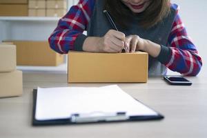 pequeño negocio propietarios son escritura nombres a preparar a entregar paquetes a clientes. pequeño negocios de venta en línea y ordenando productos en línea foto