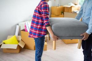 Couples helping each other to move personal belongings lifting furniture into the house. House moving ideas. photo