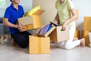 parejas son Ayudar a desempacar cajas Moviente fuera o Moviente en casa. Moviente hogar concepto foto