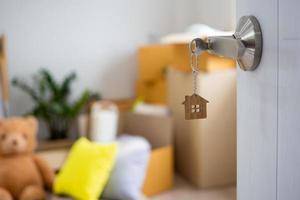 The key to the new house door that is open. With personal items after moving the house in the background photo