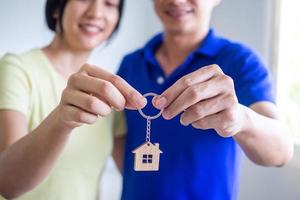 An Asian couple with a smile of happiness holds the key to a new home. photo