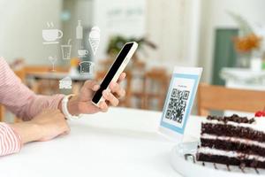 mujer utilizar teléfono inteligente a escanear qr código para orden menú en café restaurante con un digital entrega. escoger menú y orden acumular descuento. mi billetera, tecnología, pagar en línea, crédito tarjeta, banco aplicación foto