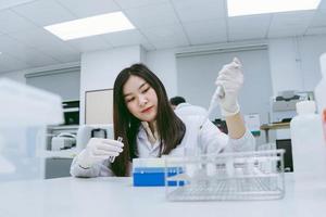 Young medical scientist working in medical laboratory , young female scientist using auto pipette to transfer sample photo