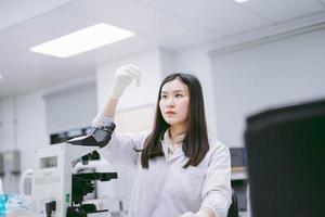 joven científica médica mirando el tubo de ensayo en el laboratorio médico foto