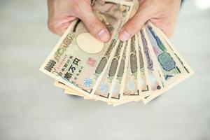 japonés yen dinero. cerca arriba de el japonés yen en mano. moneda de Japón ese es usado a cambiar, comprar, vender, acumular, invertir, financiero, intercambiar tasa, valor, contabilidad, internacional intercambiar foto