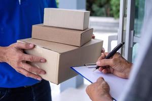 la chica compradora firma en el portapapeles para recibir la caja del paquete del repartidor. servicio de entrega rápida foto