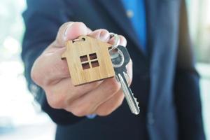 los agentes de ventas de casas están dando llaves de casa. alquilar una casa, comprar y vender concepto foto