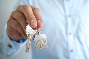 A business man with a house key. sale house concept photo