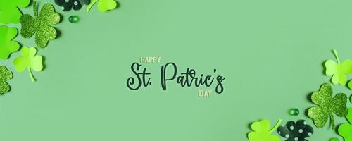 Happy St. Patrick's Day greeting text. Paper clover leaves on colored background banner format photo