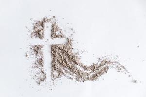 Christian cross or crucifix drawing in ash, dust or sand as symbol of religion, sacrifice, redemption, Jesus Christ, ash wednesday, lent, Good Friday, Easter with Church is devoted to fasting photo