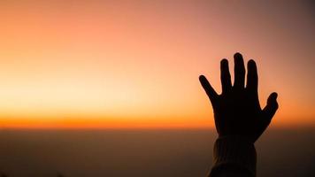 Silhouette of woman hand praying spirituality and religion, female worship to god. banner with copy space. Religious people are humble to God. Christians have hope faith and faith in god. photo