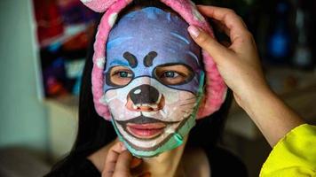 Young girl with facial mask looking at camera over interior background. Cosmetic procedure. Beauty spa and cosmetology. photo