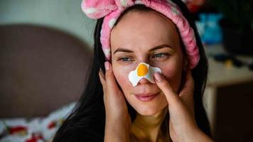 Excited lady posing with white skin stickers on nose and forehead, isolated over interior background photo