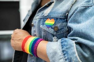 Asian lady wearing rainbow flag wristbands isolate on white background, symbol of LGBT pride month celebrate annual in June social of gay, lesbian, bisexual, transgender, human rights. photo