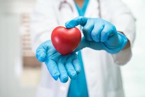 Doctor holding a red heart in hospital ward, healthy strong medical concept. photo