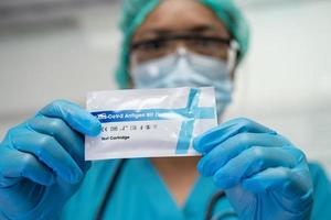 Asian doctor holding Saliva Antigen Test Kit for check Covid-19 coronavirus in hospital. photo