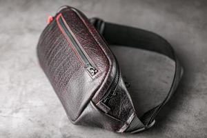 Bag on the belt of textured leather in Bordeaux colour , banana on a gray background. photo