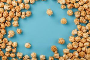 Caramel popcorn by a ripple on a blue background, in the form of a frame. photo