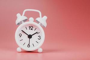 White retro alarm clock on pink background. Concept of time with free space for text. photo