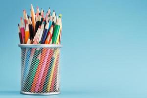 Colorful pencils in a metal jar on a blue background. photo