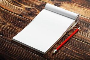 Notepad with red pencil on a brown wooden table background, for education, write goals and deeds photo