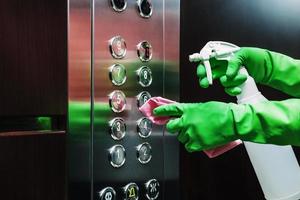 Disinfection of the elevator with a sanitizer and a napkin. photo