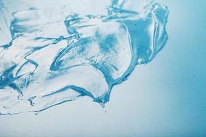 gel con hialurónico ácido en el formar de un frotis de lustroso textura en un azul antecedentes. foto