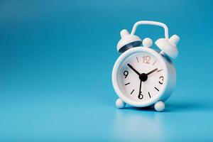 blanco retro alarma reloj en azul antecedentes. concepto de hora con gratis espacio para texto. foto