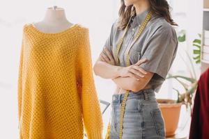 Beautiful lady blogger showing clothes in front of the camera to recording vlog video live streaming at her shop. Online Shopping Cart notion. photo