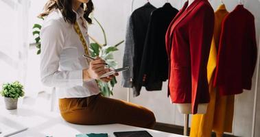 Beautiful lady blogger showing clothes in front of the camera to recording vlog video live streaming at her shop. Online Shopping Cart notion. photo