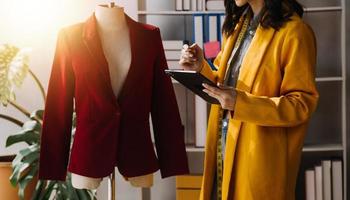 Beautiful lady blogger showing clothes in front of the camera to recording vlog video live streaming at her shop. Online Shopping Cart notion. photo