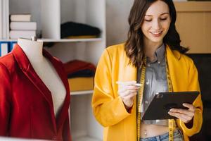 Beautiful lady blogger showing clothes in front of the camera to recording vlog video live streaming at her shop. Online Shopping Cart notion. photo