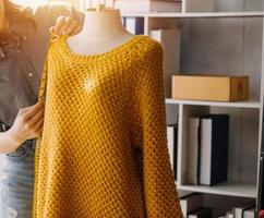 Beautiful lady blogger showing clothes in front of the camera to recording vlog video live streaming at her shop. Online Shopping Cart notion. photo