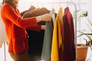 Beautiful lady blogger showing clothes in front of the camera to recording vlog video live streaming at her shop. Online Shopping Cart notion. photo