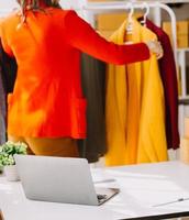 Beautiful lady blogger showing clothes in front of the camera to recording vlog video live streaming at her shop. Online Shopping Cart notion. photo