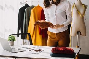 Beautiful lady blogger showing clothes in front of the camera to recording vlog video live streaming at her shop. Online Shopping Cart notion. photo