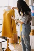 Beautiful lady blogger showing clothes in front of the camera to recording vlog video live streaming at her shop. Online Shopping Cart notion. photo