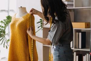 Beautiful lady blogger showing clothes in front of the camera to recording vlog video live streaming at her shop. Online Shopping Cart notion. photo