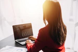 Asian Business woman using calculator and laptop for doing math finance on an office desk, tax, report, accounting, statistics, and analytical research concept photo