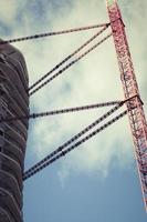 Modern unfinished multistory building and a lifting crane. photo