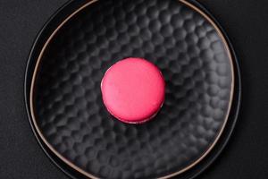 Beautiful tasty macaron with filling and fruit flavor on a black plate photo