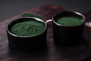 Spice, green color spirulina in the form of powder in a black bowl photo