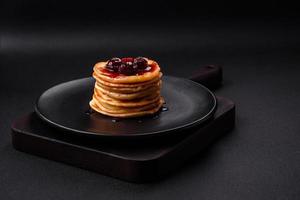 delicioso Fresco panqueques con baya mermelada en un negro cerámico plato foto