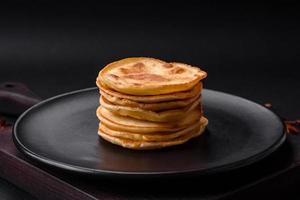 Delicious fresh pancakes with berry jam on a black ceramic plate photo