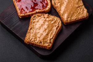 nutritivo emparedados consistente de pan, frambuesa mermelada y maní mantequilla foto