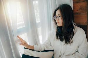 Beautiful women sitting alone on sofa in living room at home thinking contemplating look at window in morning. Relaxed sad melancholic girl feel upset quarreled with beloved man. feeling lonely, bored photo