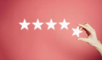 Woman's hand put the stars to complete five stars. Customer satisfaction concept. copy space and pink background. giving a five star rating. Service rating, satisfaction concept. photo