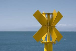 Yellow no sail metallic buoy on blue sea background photo